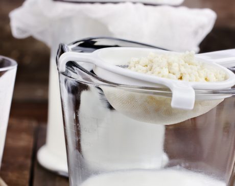 Straining milk kefir grains from milk using a fine mesh sieve.