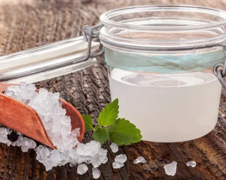 How to Make Water Kefir: Glass jar with fermented water kefir, along with kefir grains on a spoon. Explore the homemade water kefir process.